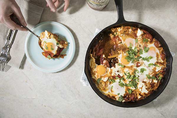 Shakshuka meal in a skillet and a plate with a serving nearby